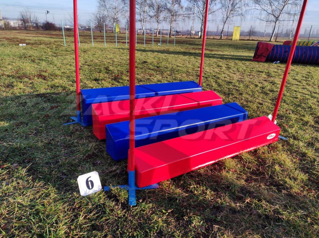 Červeno-modré molitanové překážky připravené na agility soutěži, označení stanoviště číslem 6.